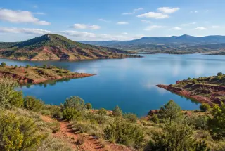 Le lac du Salagou entouré de collines volcaniques aux terres rouges sous une lumière douce.