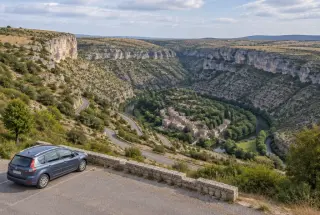 Vue panoramique du cirque de Navacelles avec une route sinueuse descendant vers le hameau et la rivière Vis.